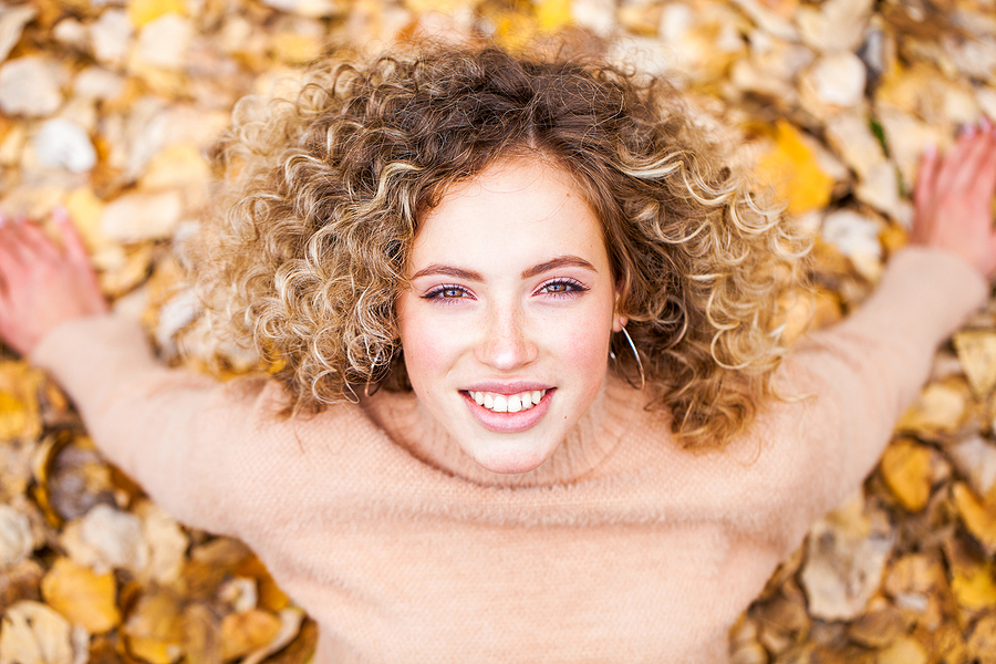 Hairstyle curly hair, portrait of a young beautiful girl in an autumn park